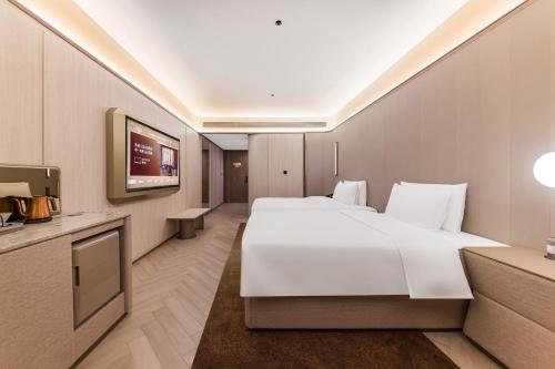 a hotel room with a large white bed and a tv at Crystal Hotel Guangzhou Huadu in Huadu