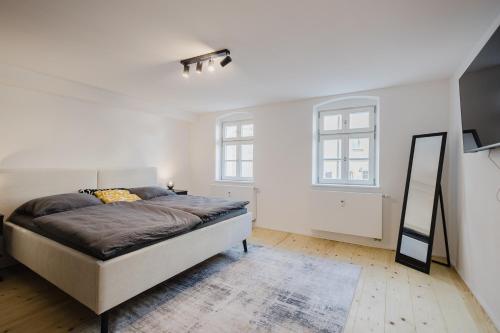 a white bedroom with a bed and a mirror at Stilvolles Wohnen am Ziegeltor - Für Gruppen, Pärchen und Singles in Amberg