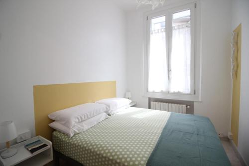 a bedroom with a bed with white sheets and a window at Appartamento La Gemma in Parma
