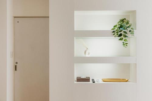 a white door with a plant sitting on a shelf at OASIS HAKATA SUITE 2 Parkings in Fukuoka