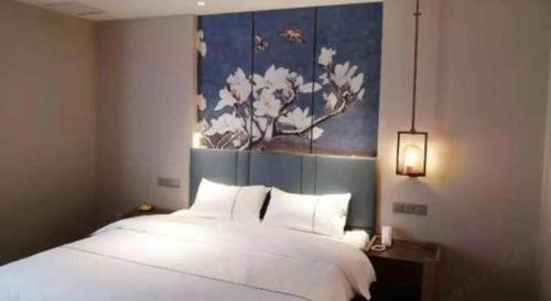 a bedroom with a white bed with a painting on the wall at Magnotel Shenyang Consulate Qingnian Street in Shenyang