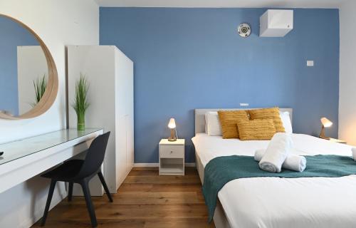 a blue room with a bed and a desk and a mirror at Yalarent C Kinneret Amazing Apartments in Migdal