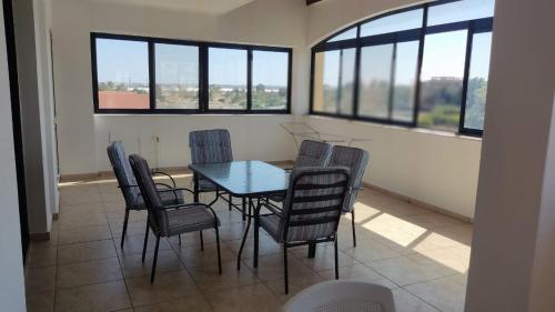 a dining room with a table and chairs and windows at 3-bedroom penthouse in Larnaka