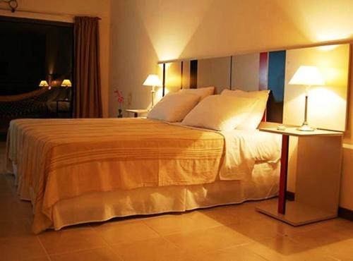 a large bed in a hotel room with two lamps at Hotel Sol Cataratas in Puerto Iguazú