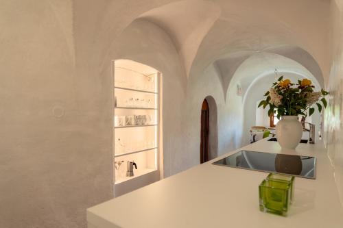 a white kitchen with a vase of flowers on a counter at zuLAVOGL in Kastelruth