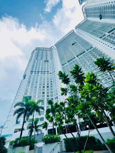 a tall building with palm trees in front of it at Novotel Hotel Residences Manila by AMORE Suites in Manila