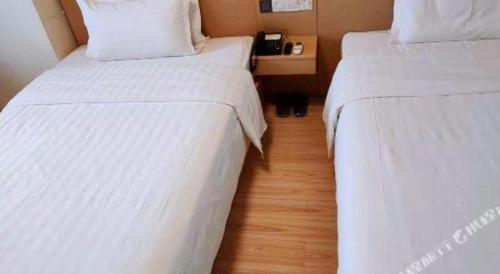 two beds in a hotel room with white sheets at 7 Days Inn Changchun Zhengyang Street Changchun Park Branch in Changchun