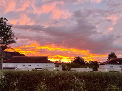 a sunset over two white buildings in a field at Plett-Dunes 41 in Keurboomstrand