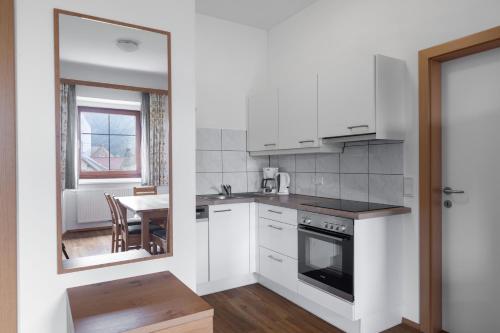a kitchen with white cabinets and a table and a window at Alte Schule in Rattendorf