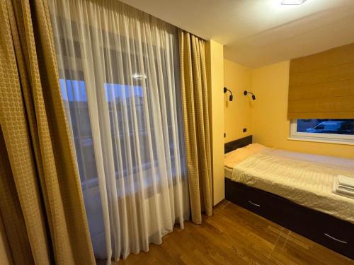 a bedroom with a bed and a window with curtains at Palanga center apartments in Palanga