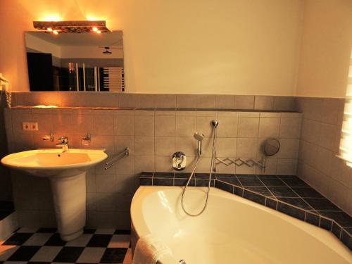 a bathroom with a sink and a bath tub and a sink at Hotel Königsseer Hof in Schönau am Königssee