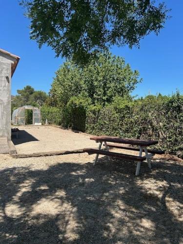 a wooden bench sitting under a tree in a park at Maison idéal Familles nombreuses in Graveson