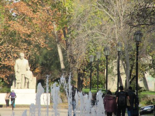 people walking around a fountain in a park with a statue at Departamento Paseo Bulnes Metro La Moneda in Santiago