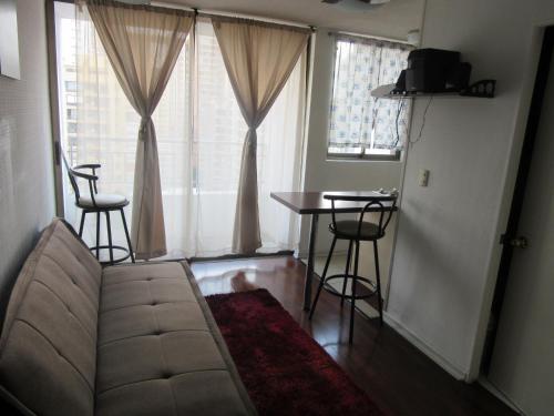 a living room with a couch and a table and windows at Departamento Paseo Bulnes Metro La Moneda in Santiago