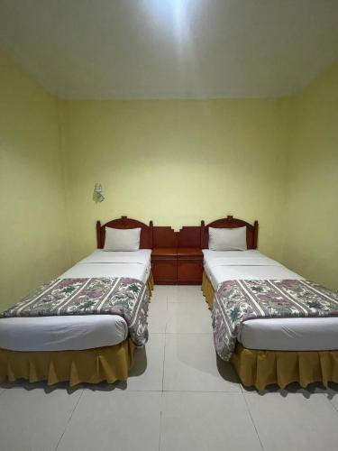 two beds in a room with green walls at Soeltan Luxe Hotel Lampung in Bandar Lampung