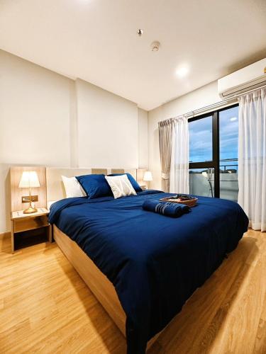 a bedroom with a large blue bed with a large window at Astra sky river five star condo in Chiang Mai
