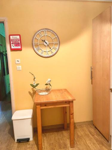 a clock on the wall next to a wooden table at Village de vacances oignies in Oignies-en-Thierache