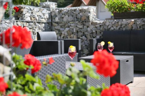 three glasses of wine on a table with red flowers at Pension Wirt am Bach in Terento