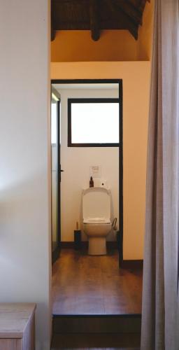 a bathroom with a white toilet in a room at Mologa River Lodge in Rust de Winter