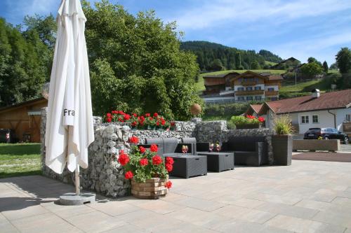 a white umbrella on a patio with red flowers at Pension Wirt am Bach in Terento
