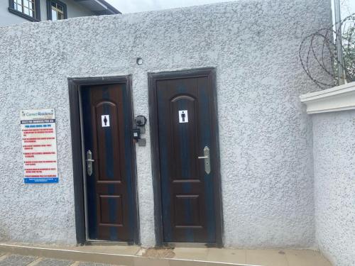 two brown doors on a white building with a sign at Correct Residence and Resort in Abuja