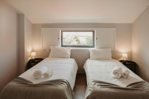 two beds in a small room with a window at Casa do Sorrio in Viana do Castelo