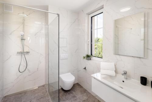 a white bathroom with a shower and a toilet at Apart House A4 Wrocław in Bielany Wrocławskie