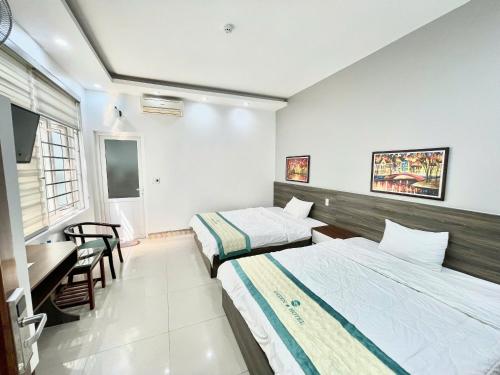 a bedroom with two beds and a table and a desk at GREEN Hotel & Coffee in Bak Kan