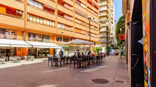 people sitting at tables and chairs outside of a building at ABAL Apartments - Barrio in Alicante