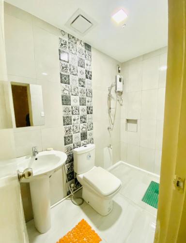 a white bathroom with a toilet and a sink at Casa Ysabel Transient Inn in Ayusan Norte