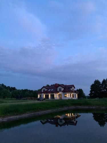 a house sitting on the side of a lake at Dworek Pod Wierzbami 