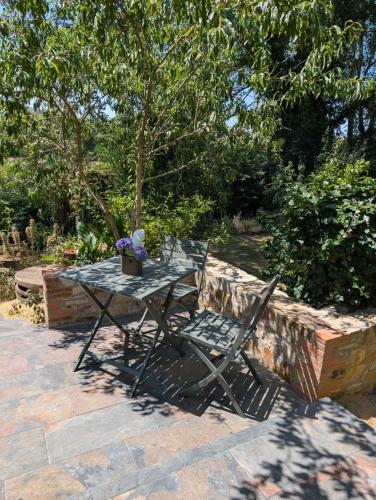a table and a chair sitting on a patio at Le gite de l'ile du Buzet in Saint-Florent-le-Vieil