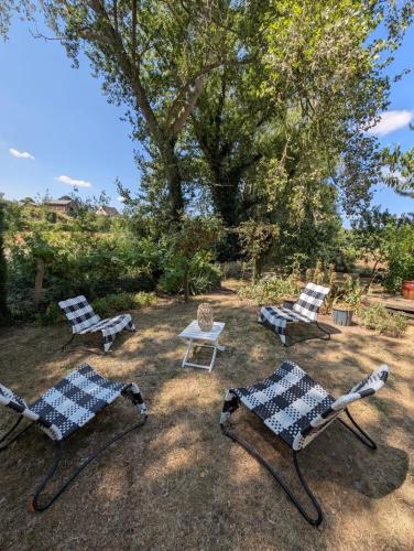 three chairs and a table in a yard with a tree at Le gite de l'ile du Buzet in Saint-Florent-le-Vieil