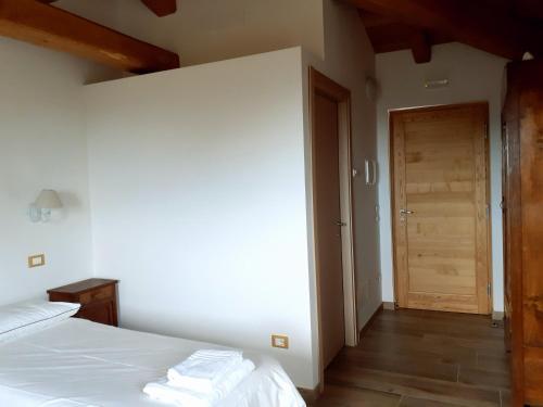 a bedroom with a white bed and a wooden door at Staulir Affittacamere in Meduno