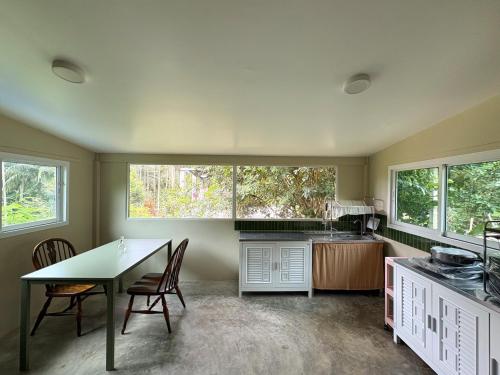 a kitchen with a table and chairs and windows at Well Living Guesthouse Khaolak in Khao Lak
