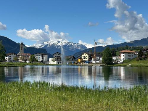 a lake with a town and a snow covered mountain at Ski in-Ski Out Studio in Laax