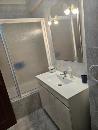a bathroom with a sink and a shower and a mirror at Âncora Guest House in Monte Gordo