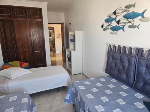 a bedroom with two beds and a cabinet with fish on the wall at Âncora Guest House in Monte Gordo