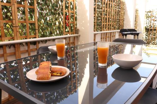 une table avec une assiette de nourriture et deux verres de jus d'orange dans l'établissement Terraza by Pom, au Cap d'Agde