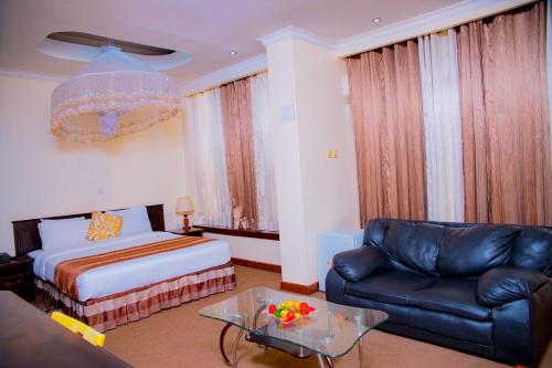 a bedroom with a bed and a couch and a table at Ineza Hotel Musanze - Snow Hotel in Ruhengeri