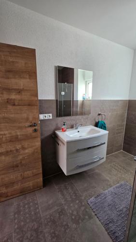 Un baño con un lavabo blanco y un espejo. en Apartmán VIVINO, en Bojnice