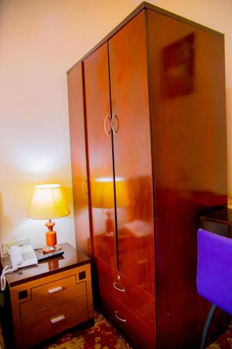 a large wooden cabinet next to a desk with a lamp at Ineza Hotel Musanze - Snow Hotel in Ruhengeri