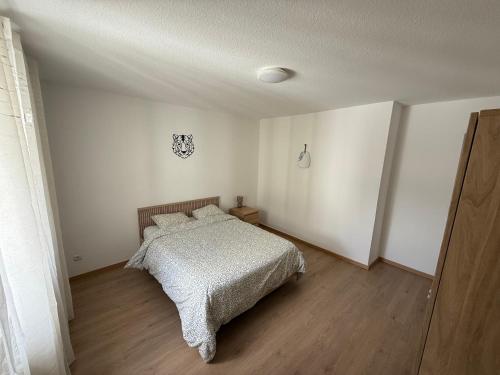 une chambre blanche avec un lit et un parquet dans l'établissement Chambre chez l'habitant - Longwy bas, à Longwy