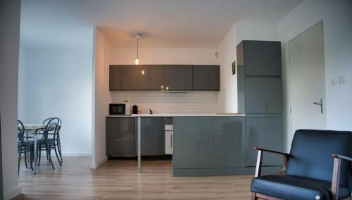 une cuisine avec des armoires grises et une table et des chaises dans l'établissement près Avignon clim parking jardin, aux Angles (Gard)