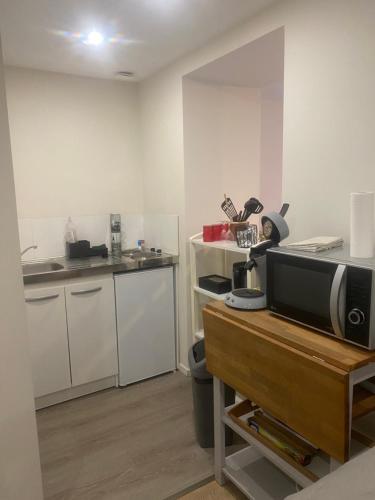 une cuisine avec des placards blancs et un four micro-ondes sur une table dans l'établissement Appartement macon proche gare avec cours, à Mâcon