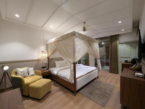 a bedroom with a canopy bed and a chair at Cape House in Amritsar