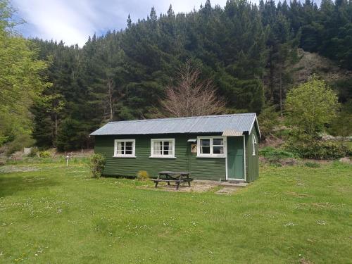 a green cabin with a picnic table in a field at Danseys Pass Holiday Park in Oamaru