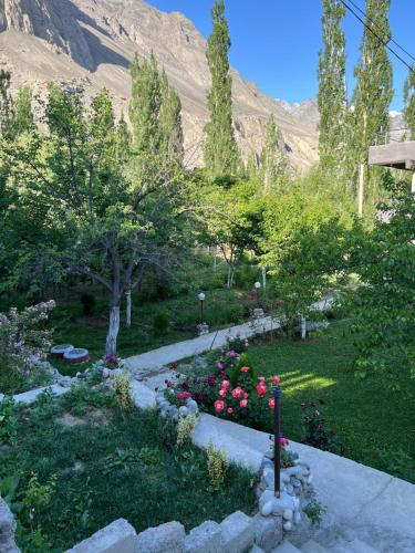 a garden with flowers and trees and a mountain at Pacific Guest House Skardu in Skardu