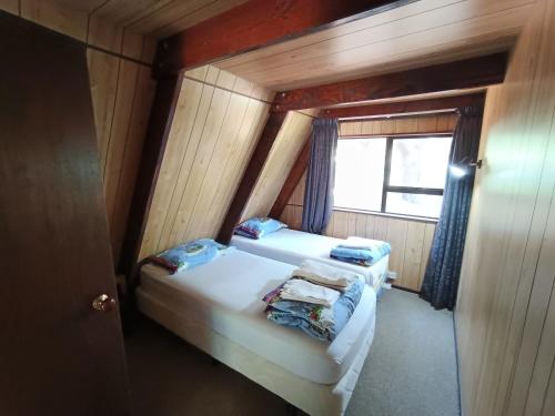 two beds in a small room with a window at Danseys Pass Holiday Park in Oamaru
