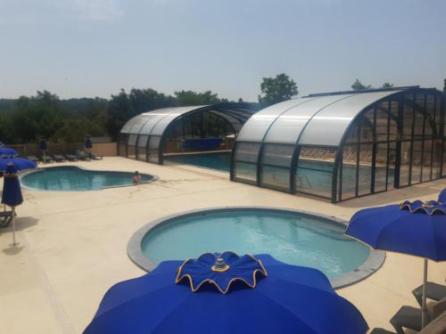 una piscina con dos sombrillas azules y dos piscinas en Mobil home des gorges de provence, en Montagnac